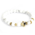 Pulsera de piedra blanca con Hamsa dorada · NŪMEN MIND